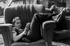 a black and white photo of a man laying on a couch with his legs crossed