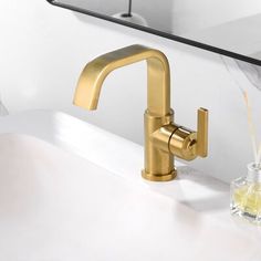 a gold faucet sitting on top of a white sink next to a mirror