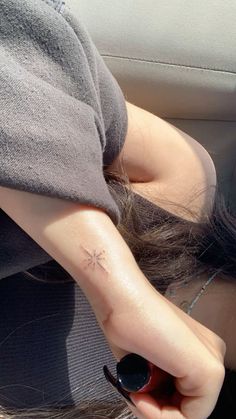 a woman with a small cross tattoo on her left arm, sitting in a car