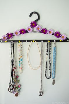 a rack with several necklaces hanging from it's sides and flowers on the top