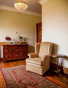 a living room with a chair, dresser and rug on the wooden floor next to it