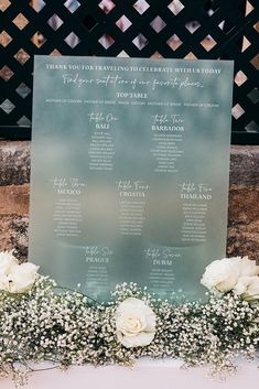 a sign with flowers and baby's breath on it sitting next to a wall