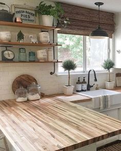 the kitchen counter is made out of wood and has shelves above it that hold plants