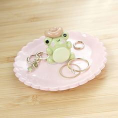 a small toy frog on a pink plate with keychain and ring holder in the shape of a heart