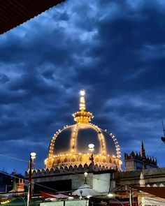 an illuminated gazebo in the middle of a city at night with dark clouds overhead