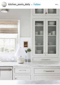 a kitchen with white cabinets and marble counter tops