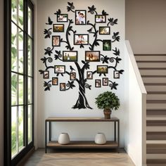 a family tree wall hanging on the side of a white wall next to a stair case