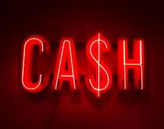 a red neon sign that says cash on it's side in front of a dark background