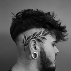 a man with a tattoo on his head and ear piercings in the shape of leaves