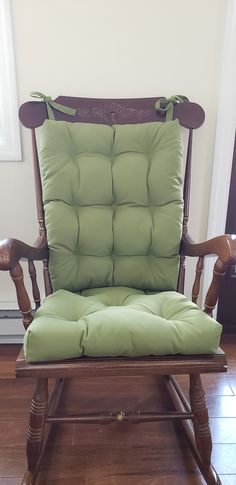 a rocking chair with a green cushion on the back and seat pad in front of it