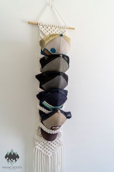 a wall hanging made out of hats on a wooden stick and string with a white background