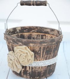 an old wooden bucket with a flower on the handle is sitting on a white wood floor