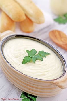 a bowl of dip with parsley on top and bread in the backgroud