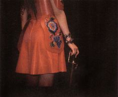 a woman in an orange dress holding a purse