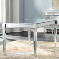 a glass table sitting on top of a rug in front of a white dresser and chair