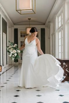 a woman in a white dress is walking down the hall with her wedding dress on