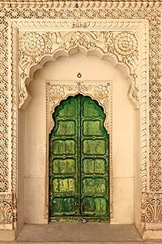 an ornate doorway with a green door in the middle