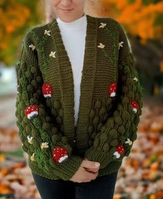 a woman wearing a green knitted cardigan with mushrooms on it