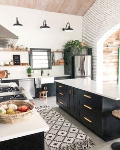 a kitchen with black cabinets and white counter tops, an island in the middle has fruit on it