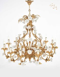 an ornate chandelier with white flowers and gold trimmings on the bottom