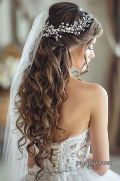 a woman wearing a wedding dress with a veil on her head and flowers in her hair