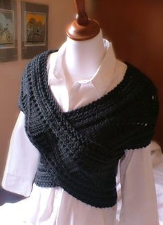 a woman wearing a black knitted shawl on top of a mannequin