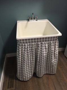 a white sink sitting under a window next to a wooden floor in a room with blue walls