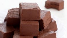 a pile of chocolate fudges sitting on top of a white plate next to another piece of cake