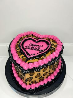 a leopard print heart shaped birthday cake with pink frosting and black icing on top