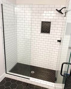 a bathroom with black and white tiles on the floor, shower stall door and toilet