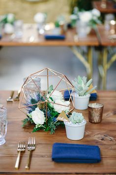 a wooden table topped with white flowers and succulents