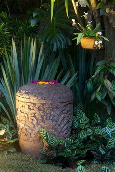 a large planter sitting in the middle of some grass and plants next to trees