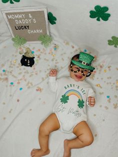 a baby in a st patrick's day outfit laying on a bed