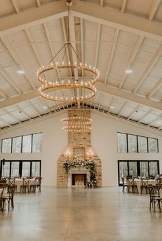 a large room with tables, chairs and a chandelier hanging from the ceiling