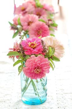 pink flowers are in a blue vase on the table