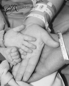 a black and white photo of two hands holding a baby's hand in the hospital