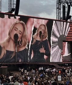 a large screen with two women singing on it in front of an audience at a concert