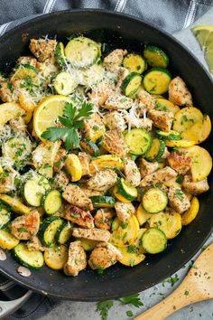 a skillet filled with chicken, zucchini and parmesan cheese