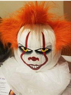 a close up of a clown's face with orange hair and makeup on it