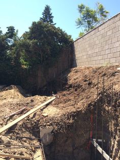 a pile of dirt sitting next to a brick wall and wooden fence on top of a hill