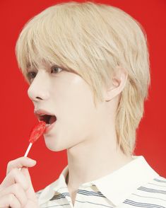 a young man holding a lollipop in his mouth