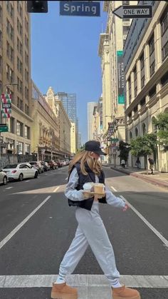 a woman walking across a street holding a cup