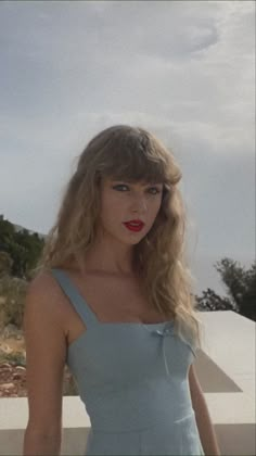 a woman in a blue dress posing for the camera with her hand on her hip