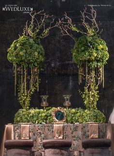 an image of a table setting with flowers and greenery on the wall behind it