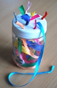 a jar filled with colorful streamers on top of a wooden table next to a toothbrush