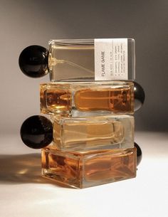 three bottles of perfume are stacked on top of each other, one is black and the other is brown