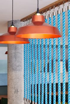 two orange lights hanging from the ceiling in a room with blue and white striped curtains