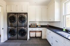 a washer and dryer in a kitchen next to a window with white cabinets