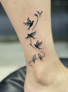 a small tattoo on the ankle with two birds flying around and flowers in the middle