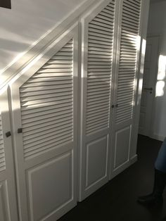 a person sitting on the floor in front of some white closets and doors with shutters